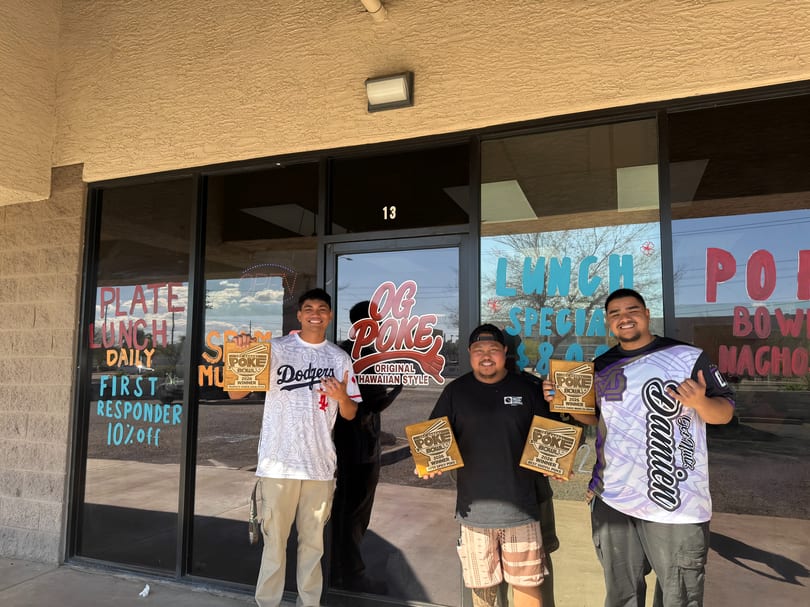 Three men proudly display their "Poke Bowl" awards outside the OG Poke restaurant.